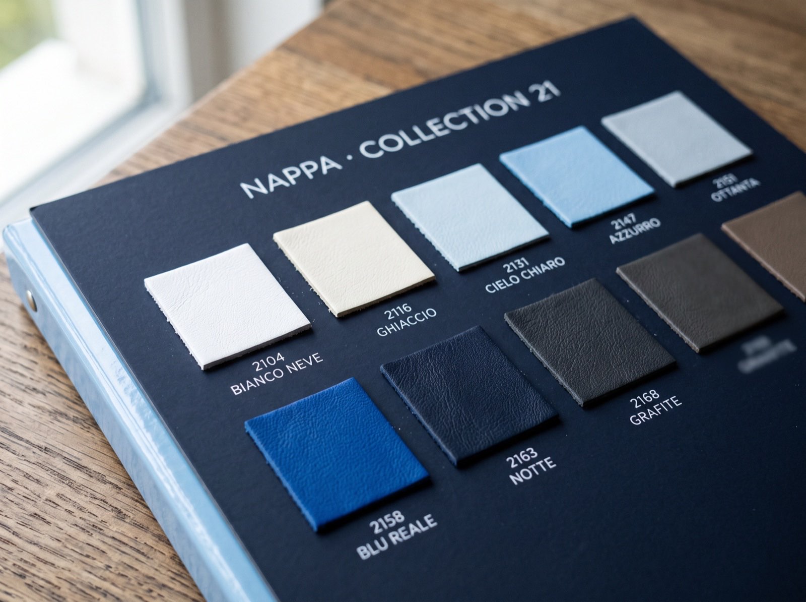 A leather maker's catalog of nappa swatches in white, ivory, blue, grey and black, each with its color name and number